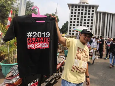 Pedagang menjual kaos #2019GantiPresiden di halaman Masjid Istiqlal, Jakarta, Jumat (10/8). Mereka memanfaatkan peluang berdagang usai deklarasi Capres dan Cawapres. (Liputan6.com/Fery Pradolo)