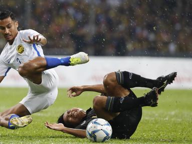 Pemain Malaysia, Muhammad Danial Amier Norhisham (kiri) berebut bola dengan pemain Thailand, Phitiwat Sookjitthummakul pada final sepak bola putra SEA Games 2017 di Stadion Shah Alam, Malaysia (29/8/2017). Thailand menang 1-0. (AP/Vincent Thian)