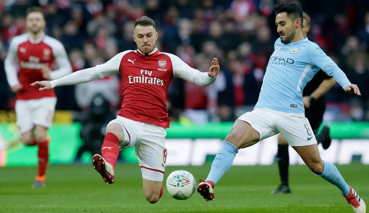 Pemain Arsenal Aaron Ramsey berebut bola dengan pemain Manchester City, Ilkay Gundogan dalam laga final Piala Liga Inggris di Stadion Wembley, Minggu (25/2). Manchester City menghancurkan Arsenal dengan skor telak 3-0. (AP/Frank Augstein)