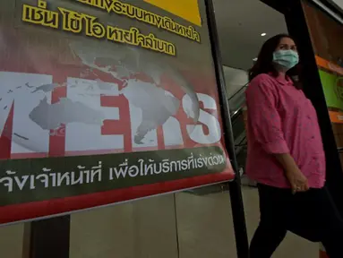 Seorang wanita Thailand berjalan memakai masker melewati pengumuman wabah MERS di Nonthaburi, Thailand, (19/6/2015). Pemerintah Thailand mengumumkan bahwa seorang pria 75 tahun asal Oman positif terjangkit virus MERS. (AFP PHOTO/Pornchai KITTIWONGSAKUL)