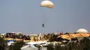 Terlihat benda-benda dengan parasut berjatuhan menuju ke tenda pengungsian warga Palestina. (Eyad BABA / AFP)