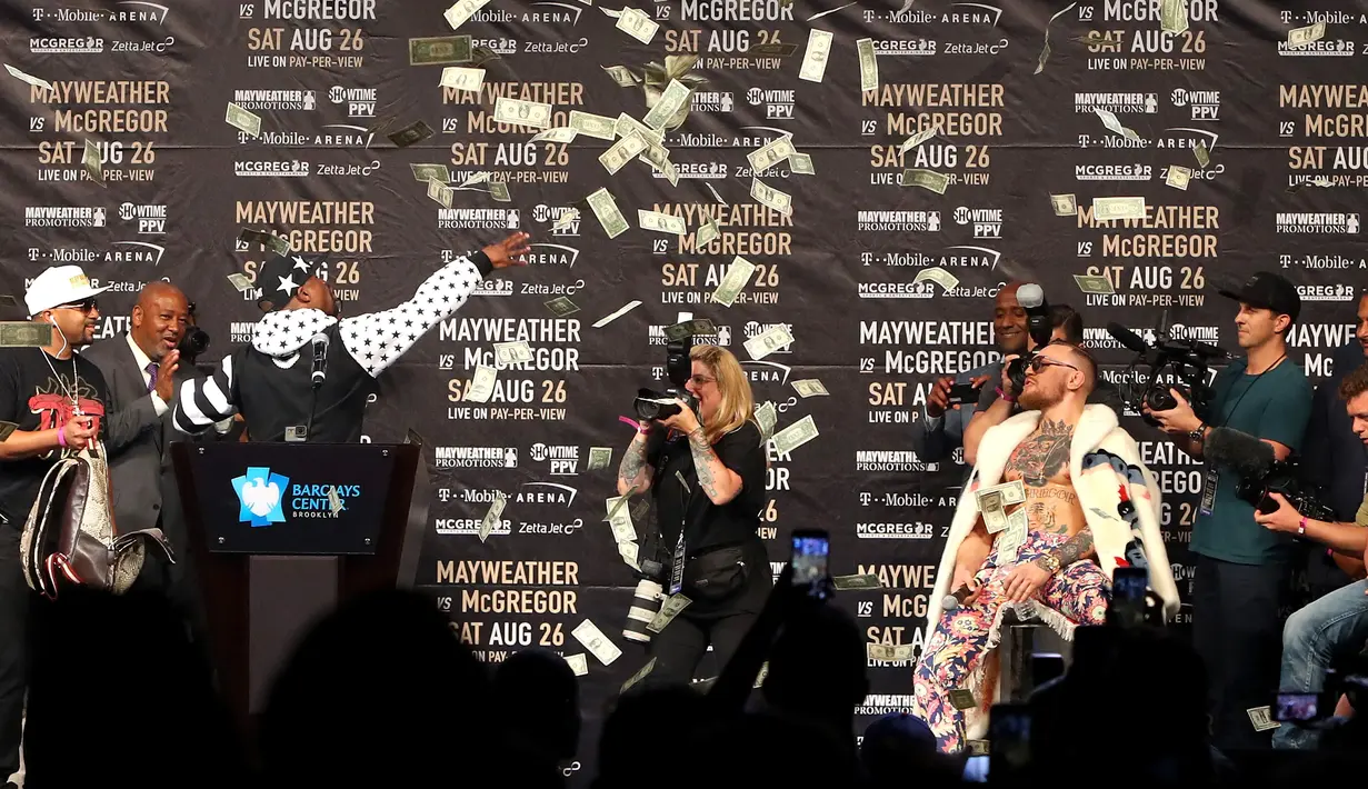 Petinju Floyd Mayweather melemparkan uang ke arah Conor McGregor saat konferensi pers tur dunia jelang pertandingannya di Barclays Center, Brooklyn, (13/7). Duel ini akan digelar di Las Vegas pada 26 Agustus. (Mike Lawrie/Getty Images/AFP)