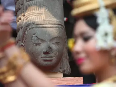 Penari menari di depan kepala patung dewa Hindu dari abad ke-7 pada upacara di Museum Nasional Kamboja, Kamis (21/1). Prancis mengembalikan kepala patung dewa yang disebut Harihara itu setelah diambil lebih dari 130 tahun lalu. (REUTERS/Samrang Pring)