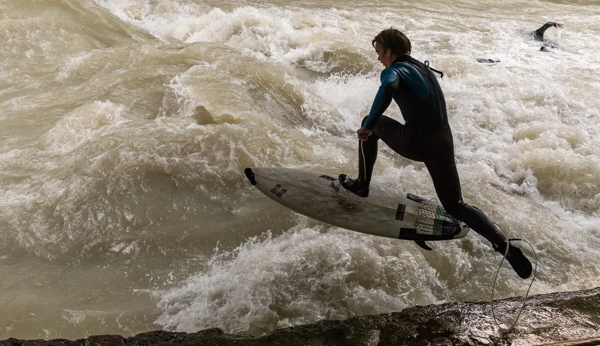 Peselancar bermain "surfing" di sungai buatan Eisbach yang terletak di English Garden Munich, Jerman pada 28 Mei 2019. Eisbach merupakan salah satu tempat berselancar sungai yang paling populer di kota Munich. (Photo by Peter Kneffel/dpa/AFP)