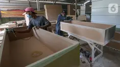 Pekerja menyelesaikan pembuatan peti mati Covid-19 di Rawa Mekar Jaya, Serpong, Tangerang Selatan, Kamis (21/01/2021). Produksi peti mati berbahan baku papan MDF meningkat cukup tinggi sejak bulan November 2020. (Liputan6.com/Fery Pradolo)