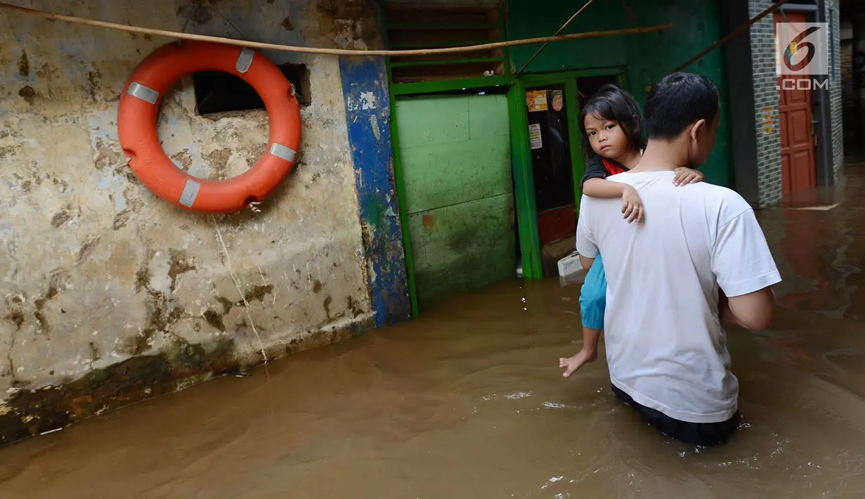 Warga menggendong putrinya melintas banjir yang merendam permukiman di Kebon Pala, Jatinegara, Jakarta, Selasa (26/2). Banjir karena Sungai Ciliwung meluap akibat air kiriman dari Bogor itu menyebabkan aktivitas warga terganggu. (Merdeka.com/Imam Buhori)