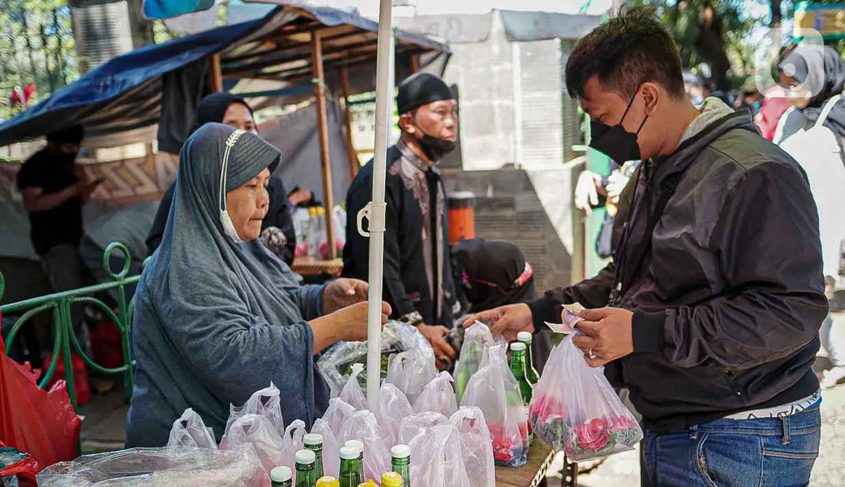 Penjual bunga tabur melayani pembeli di TPU Karet Tengsin, Jakarta, Minggu (27/3/2022). Sebagian warga memanfaatkan waktu jelang Ramadan menjadi penjual bunga tabur musiman untuk memenuhi kebutuhan ziarah ke makam yang dijual Rp 5.000 - Rp 20.000 per kantong plastik. (Liputan6.com/Faizal Fanani)