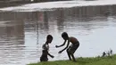 Anak-anak usai bermain sepak bola di bantaran Kanal Banjir Barat, Jakarta, Jumat (5/4). Tidak adanya lapangan menjadikan lokasi tersebut sebagai tempat bermain mereka, meskipun dalam kondisi seadanya. (Liputan6.com/Immanuel Antonius)