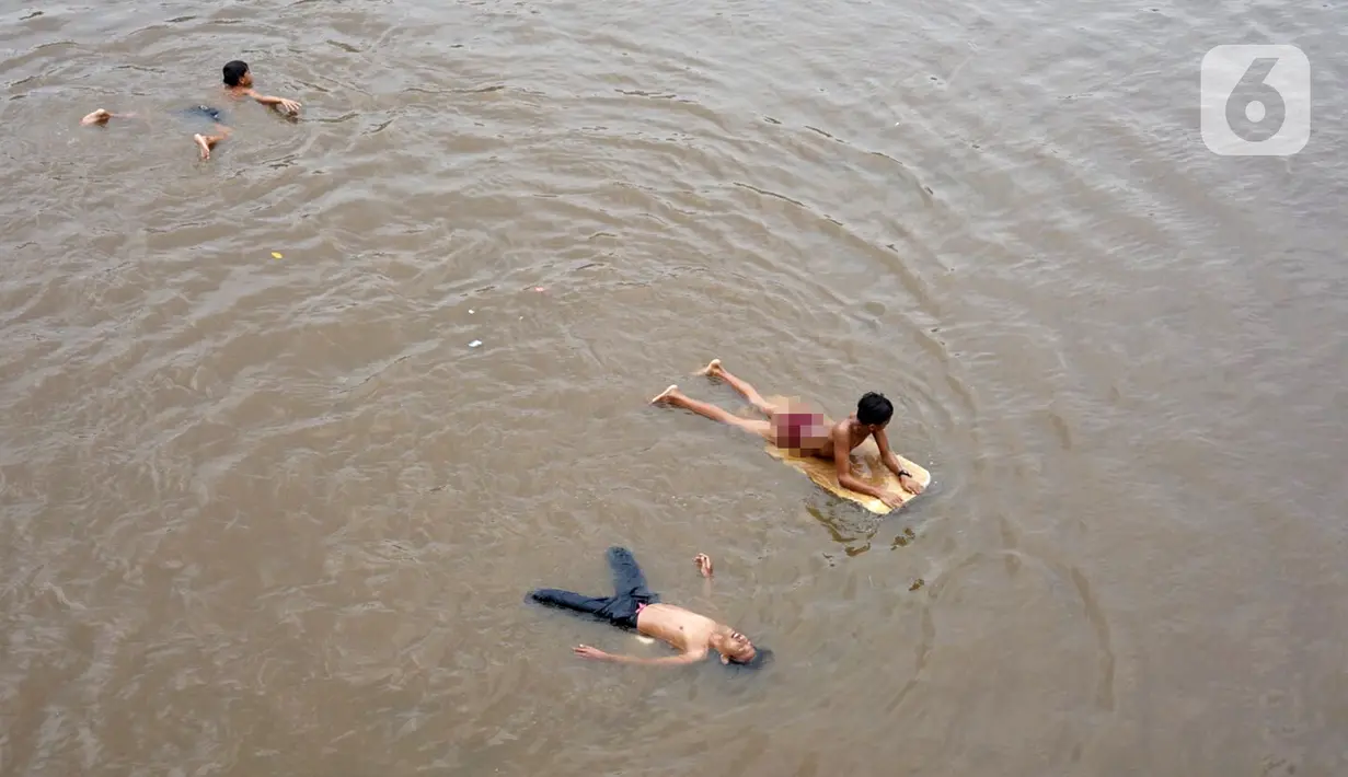 Anak-anak berenang di aliran Sungai Ciliwung, Jatinegara, Jakarta Timur, Sabtu (4/7/2020). Minimnya lahan bermain menyebabkan anak-anak tersebut bermain tidak pada tempatnya, meski dapat membahayakan keselamatan. (Liputan6.com/Immanuel Antonius)
