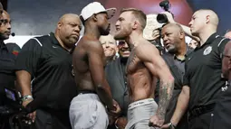 Petarung MMA, Conor McGregor dan petinju Floyd Mayweather Jr saat sesi timbang berat badan di Las Vegas, Jumat (25/8/2017). Keduanya akan bertarung pada Minggu (27/6/2017) di T-Mobile Arena, Las Vegas, Amerika Serikat. (AP/John Locher)