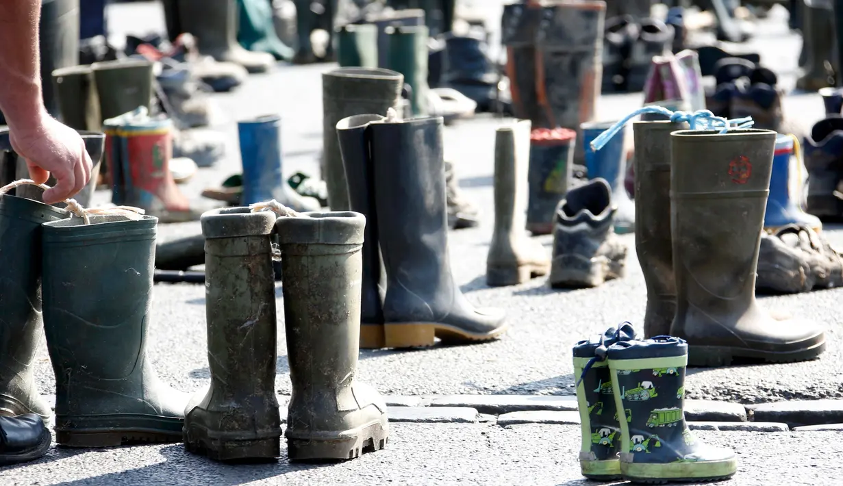 Peternak sapi meletakkan sepatu boots saat aksi protes di depan gerbang Brandenburg, Berlin, Jerman, Senin (30/5).  Mereka menuntut harga produk susu yang lebih adil bagi para peternak. (REUTERS/Fabrizio Bensch)
