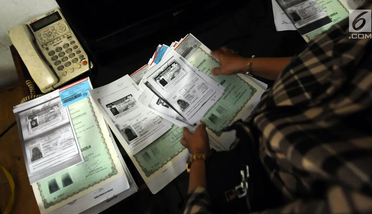 Petugas merapikan beberapa dokumen di rumah terduga penampung TKI Ilegal di Jalan Percetakan Negara X, Jakarta, Rabu (31/5). Bersama satu tersangka, petugas Dirtipidum Mabes Polri melakukan pencarian barang bukti baru. (Liputan6.com/Helmi Fithriansyah)