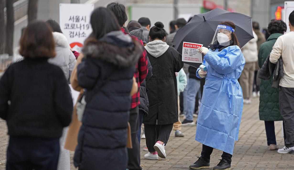 Pekerja medis memegang tanda bagi pengunjung untuk tes virus corona di klinik skrining sementara di Seoul, Korea Selatan, Jumat (10/12/2021). Otoritas kesehatan Korea Selatan melaporkan lebih dari 7.000 kasus COVID-19 baru untuk ketiga hari berturut-turut pada hari Jumat ini. (AP Photo/Lee Jin-man)
