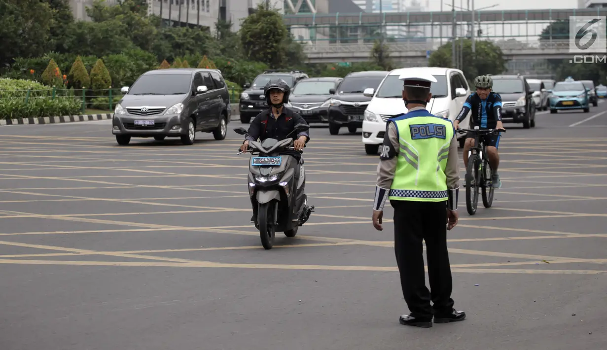 Petugas polisi berjaga saat pengendara sepeda motor melintasi Jalan MH Thamrin-Medan Merdeka Barat, Jakarta, Kamis (11/1). Mahkamah Agung (MA) membatalkan Pergub DKI tentang larangan sepeda motor melintas di jalan tersebut. (Liputan6.com/Arya Manggala)