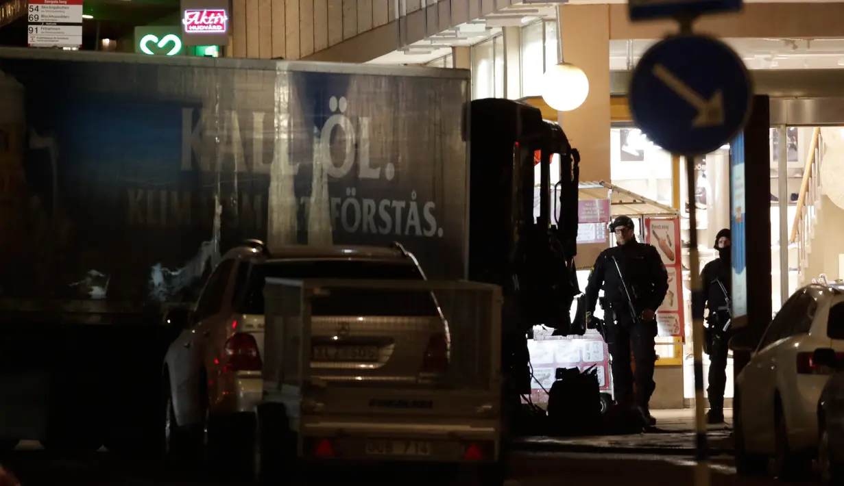 Petugas keamanan setempat berjaga di dekat truk yang menabrak kerumunan orang di Jalan Drottninggatan, pusat kota Stockholm, Swedia (8/4). Truk yang menewaskan 4 orang tersebut diketahui milik perusahaan bir Spendrups. (AP Photo / Markus Schreiber)