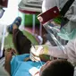 Dokter menggunakan APD memeriksa gigi pasien anak di klinik Medikids kawasan Kemang, Jakarta Selatan, Selasa (7/7/2020). Pelayanan dokter gigi dengan menggunakan APD lengkap  untuk memenuhi protokol kesehatan guna mencegah penyebaran covid-19 di era kenormalan baru. (Liputan6.com/Faizal Fanani)