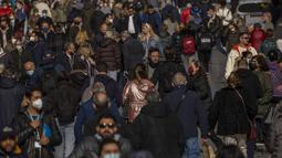 Orang-orang, beberapa dari mereka tanpa masker, berjalan di sepanjang jalan di pusat kota Madrid, Kamis (10//2/2022). Warga Spanyol untuk pertama kalinya dalam hampir dua bulan diperbolehkan tidak menggunakan masker di luar ruangan setelah peraturan terkait hal itu dicabut. (AP Photo/Manu Fernandez)