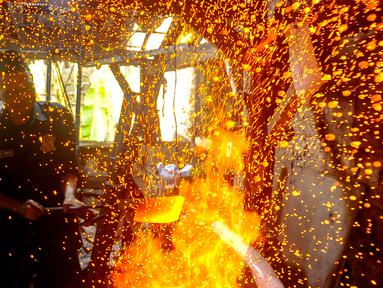 Perajin menempa logam besi saat membuat pisau khusus sembelih hewan kurban di Bengkel Tempa dan Asah Bilah HM, Jalan Akasia, Pamulang Timur, Tangerang selatan, Kamis (13/6/2024). (merdeka.com/Arie Basuki)