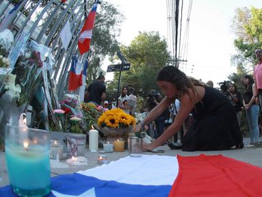 Seorang pendukung mantan Presiden Chile Sebastian Pinera meletakkan bunga di tugu peringatan untuk mengenangnya di luar rumahnya di Santiago pada tanggal 6 Februari 2024. (RAUL BRAVO/AFP)