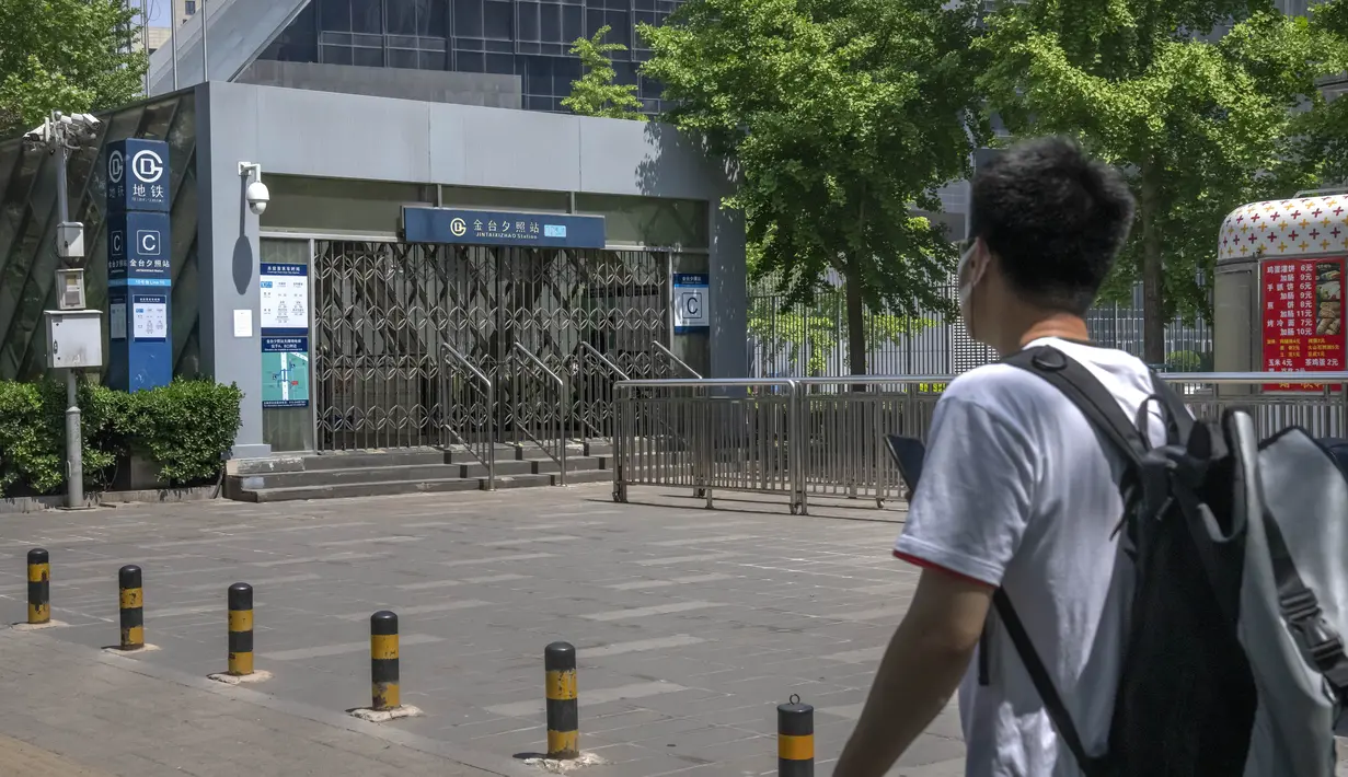 <p>Seorang pria yang mengenakan masker melihat ke pintu keluar stasiun kereta bawah tanah yang tertutup di Beijing, China Rabu (4/5/2022). Beijing pada hari Rabu ini menutup lebih dari 40 stasiun kereta bawah tanah, sekitar sepersepuluh dari jaringan kereta, sebagai bagian dari tindakan untuk menghentikan penyebaran Covid-19. (AP Photo/Mark Schiefelbein)</p>