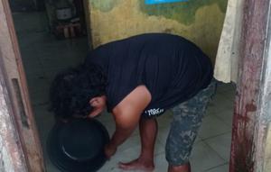 Seorang warga Kampung Sentral, Rangkasbitung, Kabupaten Lebak, yang menjadi langganan banjir sedang menyerok air yang masuk ke rumahnya. (Liputan6.com/ Dok Is Mansur)