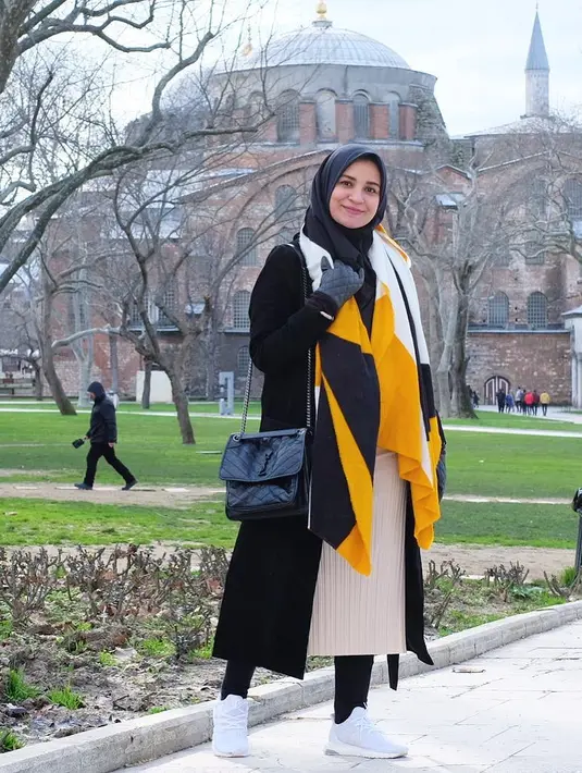 Selanjutnya, di foto ini terlihat Shireen mengenakan long outer tebal berwarna hitam dengan dalaman blouse tunik dan celana panjang. Kemudian, Shireen menambahkannya dengan scarf tebal agar terasa lebih hangat. (Instagram/shireensungkar)