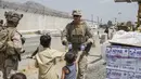 Tentara Korps Angkatan Laut AS bersama anggota Gugus Tugas Marinir Udara-Darat Tujuan Khusus di Pusat Komando, memberikan air minum kepada anak-anak saat evakuasi penduduk di bandara internasional Hamid Karzai, Kabul, Afghanistan (20/8/2021).  (Lance Cpl. Nicholas Guevara/U.S. Marine Corps via AP)