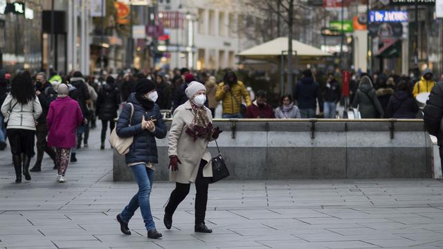 Orang-orang memakai masker saat mereka berjalan di jalan perbelanjaan di Wina, Austria, Rabu (17/11/2021).  Pemerintah Austria menetapkan penguncian nasional atau lockdown bagi warga yang tidak atau belum divaksinasi Covid-19. (AP Photo/Michael Gruber)