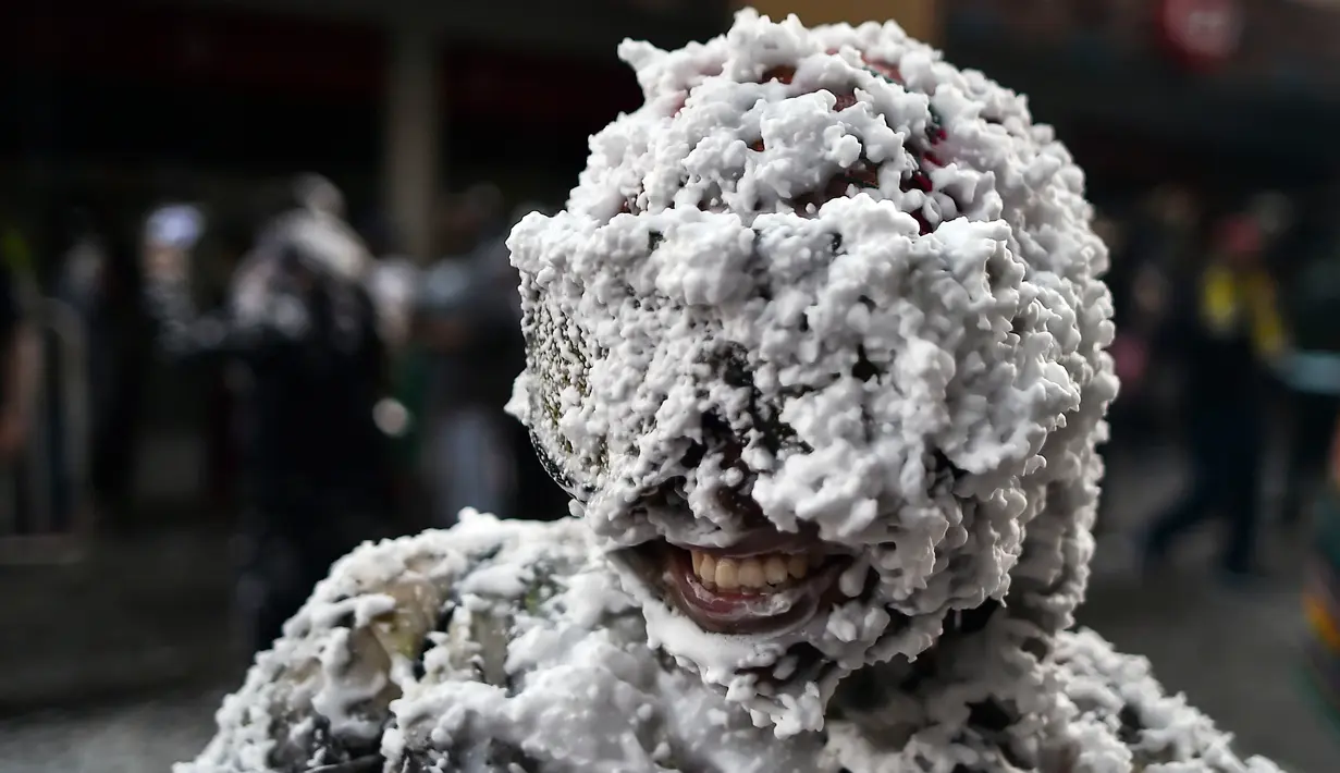 Warga bermain dengan busa, bedak, dan cat hitam selama Black Day atau Hari Hitam di Pasto, Kolombia, (5/1). Hari Hitam merupakan bagian dari karnaval orang kulit hitam dan kulit putih. (LUIS ROBAYO/AFP)