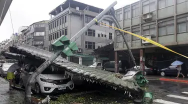 Seorang pria melihat mobil yang rusak akibat angin kencang Topan Soudelor di Taipe, Taiwan, (8/8/2015). Empat orang tewas akibat peristiwa angin kencang Topan Soudelor dan hujan deras.  (REUTERS/Pichi Chuang)
