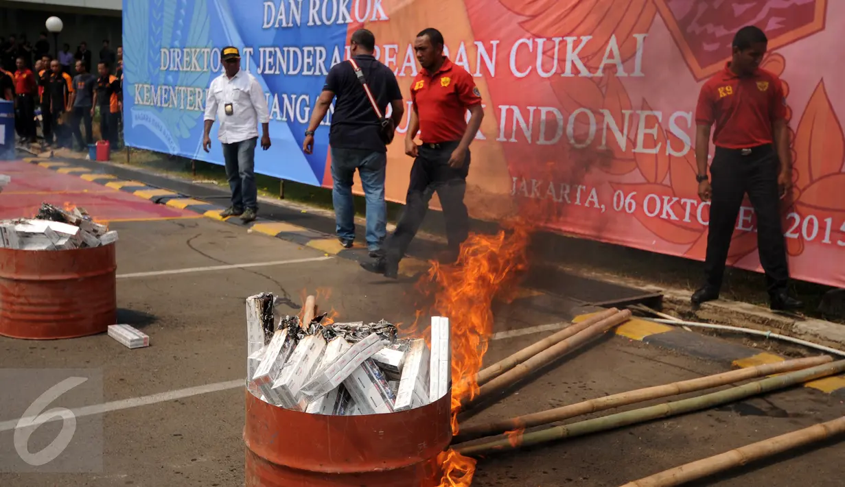 Petugas Ditjen Bea Cukai membakar beberapa boks rokok ilegal hasil sitaan Kantor Wilayah Bea Cukai Jakarta, Selasa (6/10/2015). Ditjen Bea Cukai berhasil mengamankan 12.967 botol miras dan dua juta batang rokok illegal. (Liputan6.com/Helmi Fithriansyah)