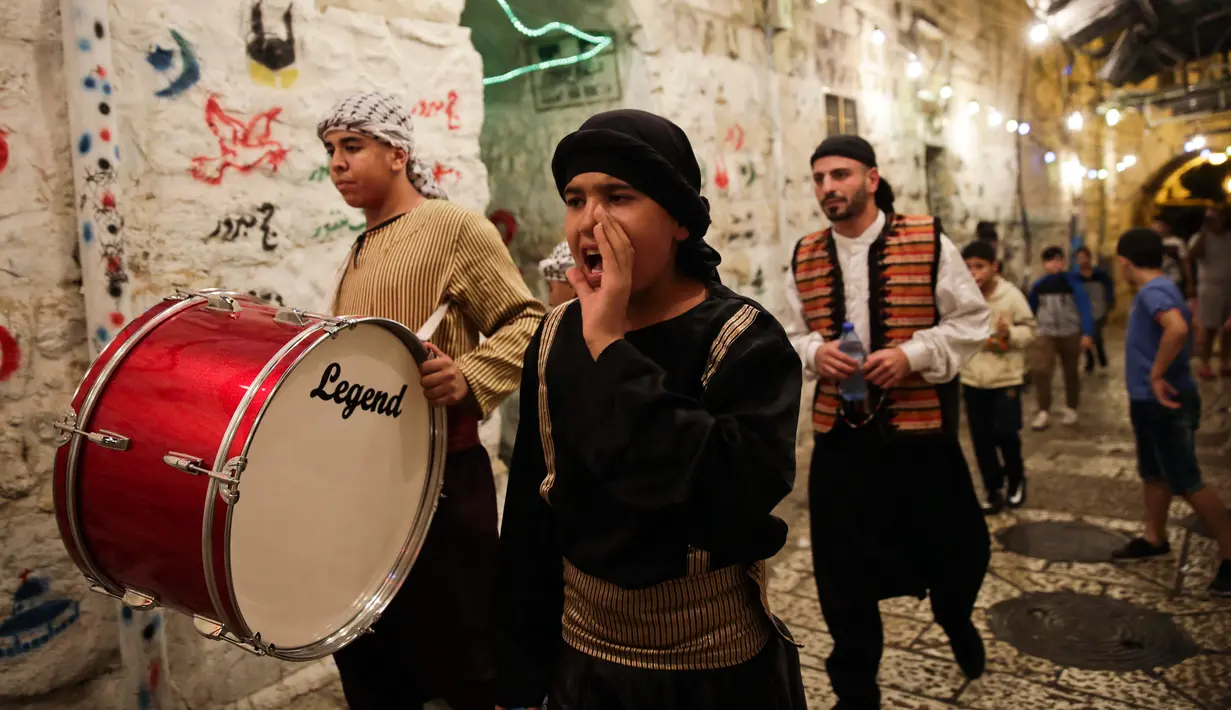 Kelompok pemuda Palestina memukul gendang ketika membangunkan kaum muslim untuk sahur di Kota Tua Yerusalem, Selasa (5/6). Dalam tradisi Musaharati ini, biasanya mereka memakai alat musik sambil menyanyikan lagu-lagu religius. (AP/Mahmoud Illean)