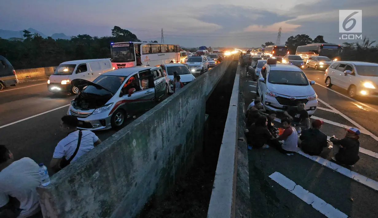 Pemudik beristirahat sembari menyantap makanan untuk berbuka puasa di pinggir ruas jalan tol Cipali KM 187, Kabupaten Cirebon, Jawa Barat, Kamis (30/5/2019). Sejumlah pemudik memilih menggunakan bahu jalan ruas tol untuk berbuka puasa karena penuhnya rest area. (Liputan6.com/Herman Zakharia)