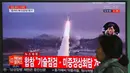 Seorang wanita melewati layar televisi yang menyiarkan berita peluncuran rudal oleh Korea Utara (Korut), di sebuah stasiun kereta di Seoul, Korea Selatan, Selasa (5/4). Rudal itu ditembakkan dari wilayah timur Korut ke arah Laut Jepang. (JUNG Yeon-Je/AFP)
