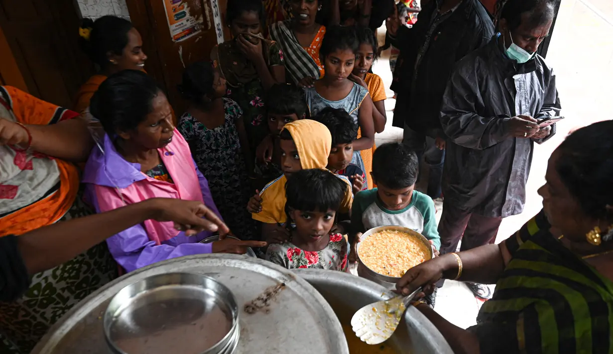 Otoritas sipil mendistribusikan makanan kepada penduduk di tempat penampungan sementara setelah hujan lebat di Chennai, India (8/11/2021). Hujan lebat terus menyebabkan genangan air di Chennai dan daerah sekitarnya. (AFP/Arun Sankar)