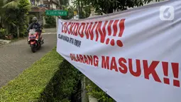 Pengendara motor melintasi spanduk pemberitahuan lockdown di RT 04 / RW 09 Kelurahan Pondok Karya, Tangerang Selatan, Rabu (23/6). Melonjaknya kasus covid-19 di beberapa kawasan membuat sejumlah wilayah melakukan karantina di tingkat RT untuk memutus penyebaran corona (Liputan6.com/Angga Yuniar)