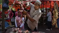 Pedagang memotong daging sapi dagangannya pada perayaan tradisi Meugang Ramadan 1440 Hijriah di Banda Aceh, 4 Mei 2019. Meugang merupakan tradisi turun temurun masyarakat Aceh dengan membeli, mengolah, hingga menyantap daging bersama keluarga. (CHAIDEER MAHYUDDIN/AFP)