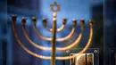 Sebuah foto yang menunjukkan menorah Hanukkah milik keluarga Posner dari Kiel dengan bendera swastika besar tergantung dari fasad bangunan di seberangnya dipamerkan dalam pameran barang-barang peringatan Holocaust di Parlemen Jerman Bundestag, Berlin, Jerman, 23 Januari 2023. Pameran untuk memperingati 70 tahun Yad Vashem, peringatan resmi Israel untuk orang-orang Yahudi korban Holocaust sejak 1953, menghadirkan berbagai benda sehari-hari yang dibawa oleh orang Yahudi ketika mereka melarikan diri dari Nazi. (AP Photo/Markus Schreiber)