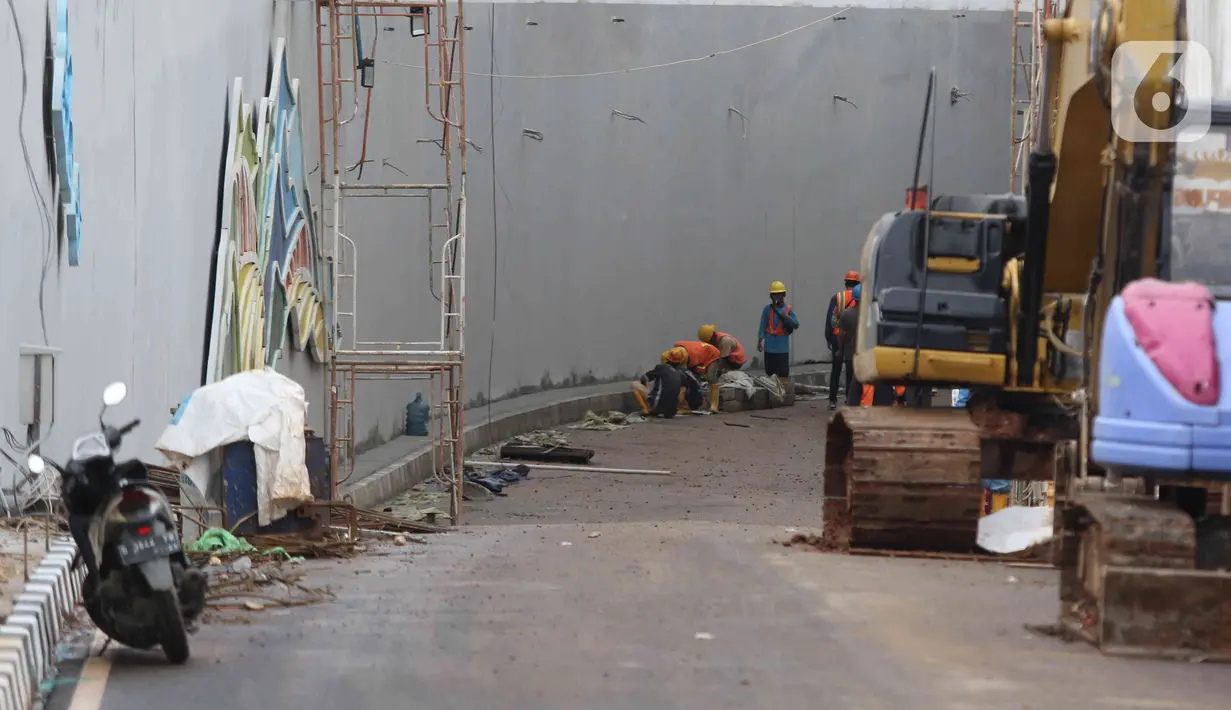 Pekerja menyelesaikan proyek pembangunan Underpass Jalan Dewi Sartika di Depok, Jawa Barat, Selasa (3/1/2023). Pembangunan underpass Jalan Dewi Sartika sepanjang 470 meter tersebut itu masih terdapat beberapa hal yang belum terselesaikan seperti trotoar, median jalan, dan pepohonan yang sebelumnya direncanakan akan selesai pada akhir tahun 2022. (Liputan6.com/Herman Zakharia)