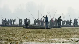 Nelayan Kashmir mencari lokasi menangkap ikan di Danau Anchar, pinggiran Srinagar, India, 28 Desember 2017. Para nelayan itu menggunakan taktik menangkap ikan dengan menutupi kepala dan sebagian tubuhnya memakai selimut dan jerami. (TAUSEEF MUSTAFA/AFP)