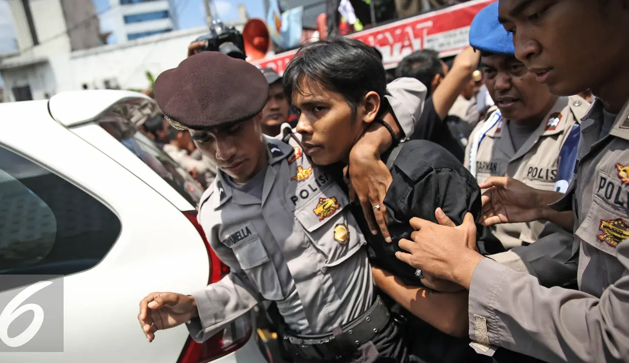 Aparat mengamankan  massa aksi dari Front Pancasila saat berusaha masuk menuju Hotel Aryaduta, Jakarta, Senin (18/4). Mereka menolak Simposium PKI yang bertentangan dengan Pancasila dan UUD 1945. (Liputan6.com/Faizal Fanani)