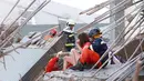 Petugas penyelamat membantu wanita di gedung apertemen yang runtuh akibat gempa 6,4 SR  di Tainan, (6/2). Menurut data meteorologi gempa terjadi pada kedalaman 16,7 kilometer di bawah permukaan laut. (REUTERS/Stringer)