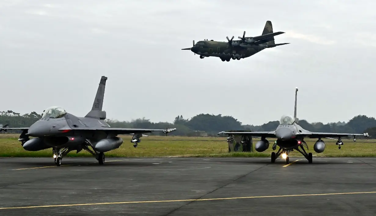Pesawat tempur F-16V bersenjata bersiap saat pengangkut personel C-130 (atas) terbang di atas pangkalan angkatan udara, Chiayi, Taiwan, 5 Januari 2022. Militer Taiwan menggelar latihan tempur darat, laut, dan udara di tengah ketegangan dengan China. (Sam Yeh/AFP)