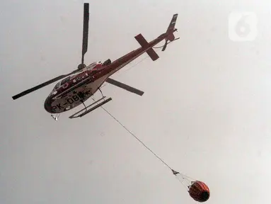 Helikopter water bombing Badan Nasional Penanggulangan Bencana (BNPB) melakukan pemadaman di Tempat Pembuangan Akhir (TPA) Rawa Kucing, Neglasari, Kota Tangerang, Banten, Senin (23/10/2023). Hingga hari keempat, proses pemadaman api terus dilakukan. (merdeka.com/Arie Basuki)