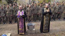 Pendeta Aristakes Hovhannisyan (kiri) dan Sebeos Galachyan melakukan upacara pembaptisan untuk tentara etnis Armenia di sebuah kamp militer dekat garis depan konflik di wilayah separatis Nagorno-Karabakh, Azerbaijan, Senin (2/11/2020). (AP Photo)