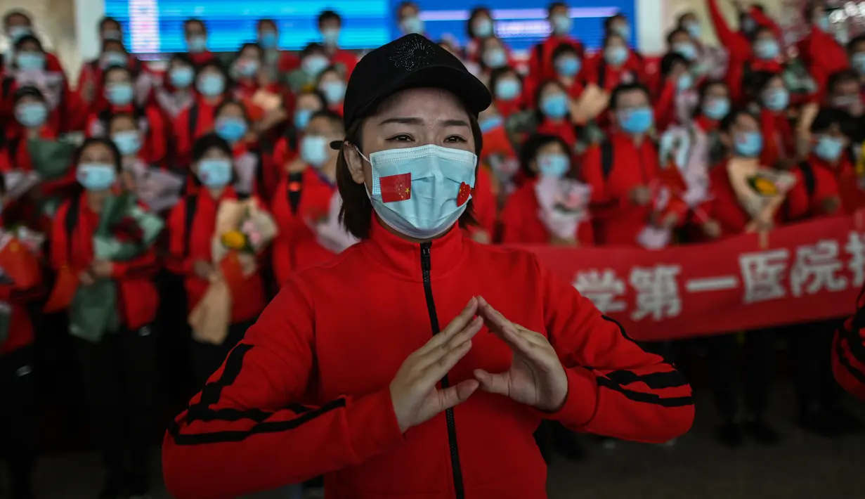 Staf medis dari Provinsi Jilin yang menangani pandemi Covid-19 berpartisipasi dalam upacara pelepasan di Bandara Tianhe, Wuhan, provinsi Hubei, Rabu (8/4/2020). Pemulangan staf medis ini bersamaan dengan pencabutan lockdown di Wuhan yang telah diberlakukan selama 11 minggu. (Hector RETAMAL/AFP)
