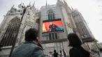 Pejalan kaki melewati layar di katedral Duomo yang menunjukkan model Moschino selama Milan Digital Fashion Week, di Milan, Italia, 14 Juli 2020. Empat puluh rumah mode menampilkan koleksi pakaian untuk musim semi/musim panas 2020 dalam format digital di tengah pandemi Covid-19. (AP Photo/Luca Bruno)
