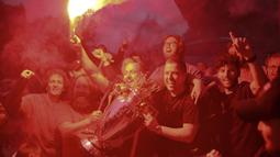 Fans Liverpool merayakan gelar juara Premier League di area Standion Anfield usai pertandingan Liverpool melawan Chelsea, Kamis (23/7/2020) dini hari WIB. Fans Liverpool tetap berdatangan ke area Stadion Anfield meski ada permintaan untuk merayakan di rumah. (AFP/Oli Scarff)