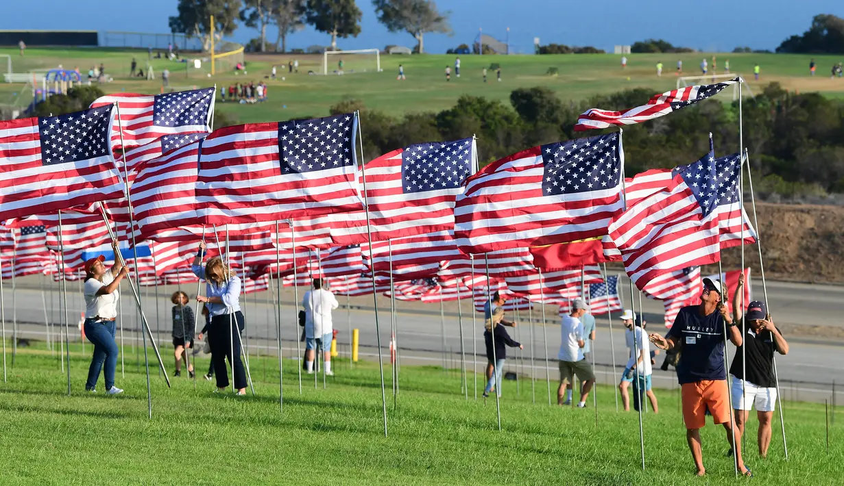 Orang-orang membantu pengibaran bendera AS untuk peringatan 20 tahun serangan 9/11 di Pepperdine University di Malibu, California, Rabu (8/9/2021). Selama 14 tahun, universitas itu memperingati tragedi 11 September 2001 dengan mengibarkan sekitar 3.000 bendera Amerika. (Frederic J. BROWN/AFP)