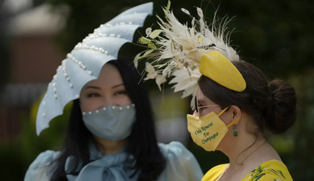 Anna Gilder (kanan) bersama Yuan Li berpose untuk fotografer mengenakan topi hiasan mereka pada hari pertama pacuan kuda Royal Ascot di Ascot, Inggris, Selasa (15/6/2021). Balap kuda eksklusif yang hanya dihadiri kalangan elit Inggris itu menjadi tradisi tahunan sejak 1711. (AP Photo/Alastair Grant)